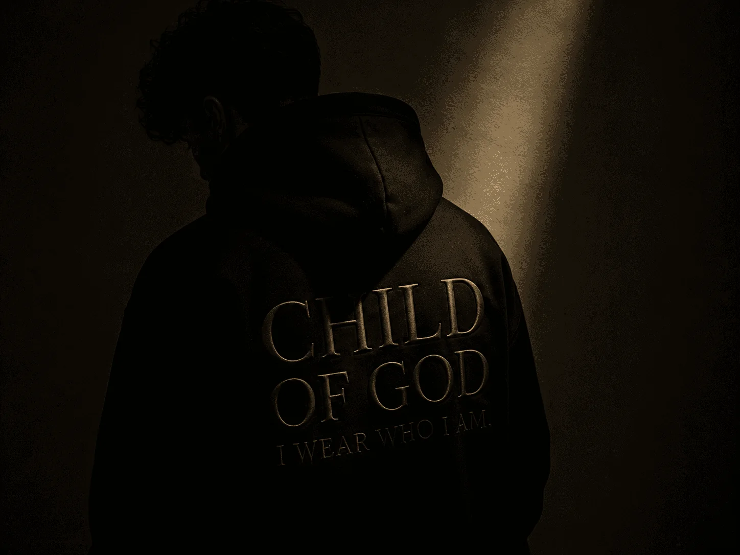 A man seen from behind wearing the black Identity Hoodie, with CHILD OF GOD and I WEAR WHO I AM embroidered on the back